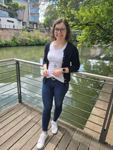 Eva Brucksch, Coach für Positive Leadership, steht lächelnd in einem legeren Business-Outfit an einem Flussufer.